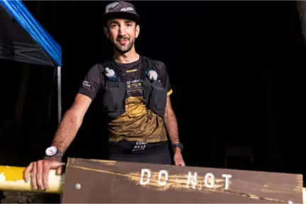 Aurélien Sanchez, ultra-traileur français, debout après une boucle épuisante de la Barkley 2025, vêtu de son équipement de course, sous une tente de contrôle de nuit.